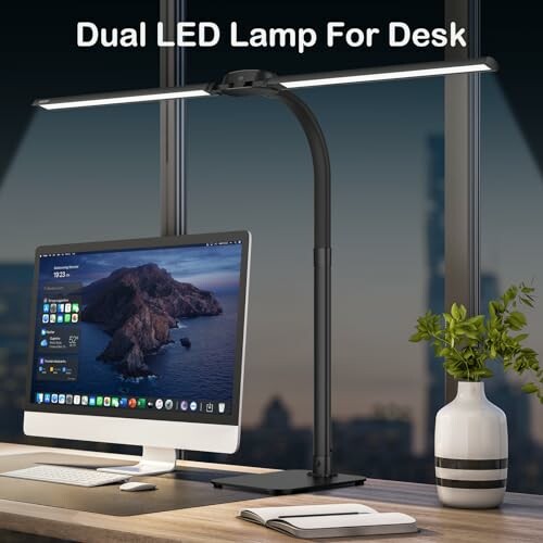 Desk with dual LED lamp, computer, and plant.